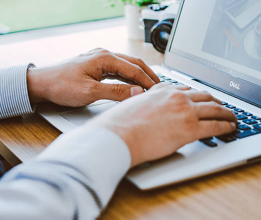 A person sitting in front of a laptop typing.