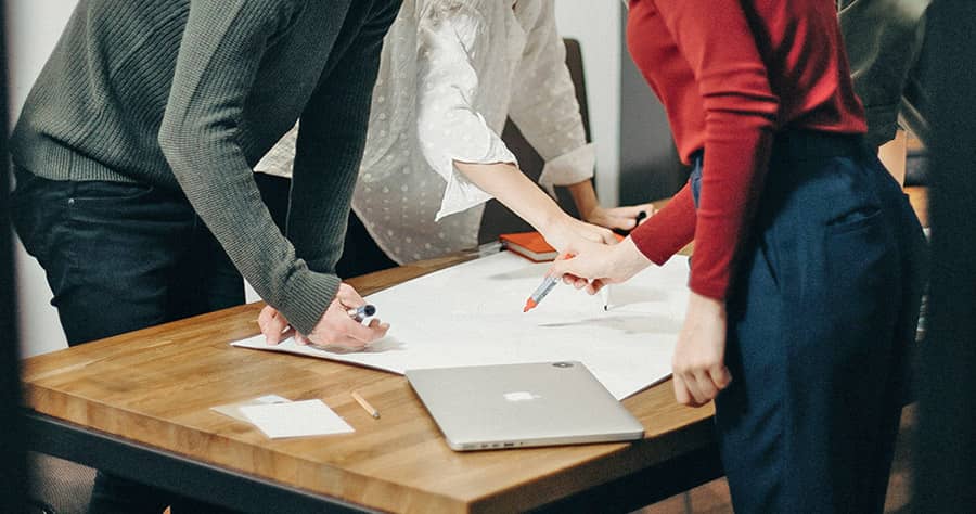 A group of people standing around a table discussing a project.